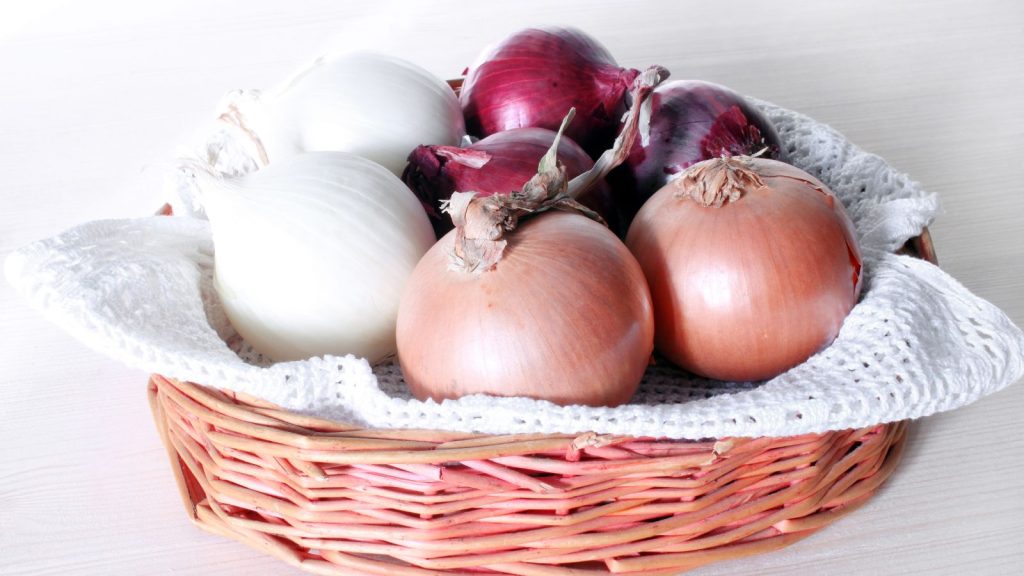 Red, white and yellow onions in a basket